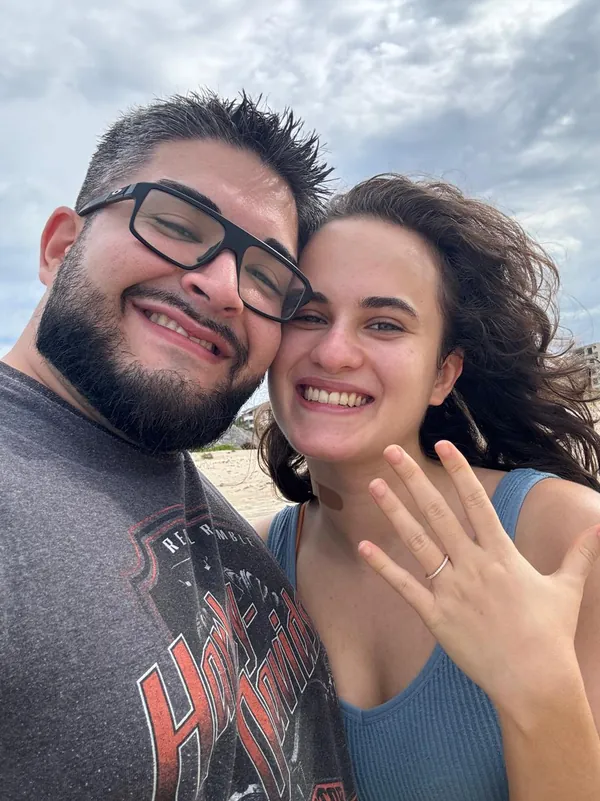 Selfie do casal na praia; Isabel mostra o anel de noivado.
